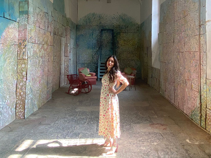 A woman in a sundress stands in a large, open art studio.