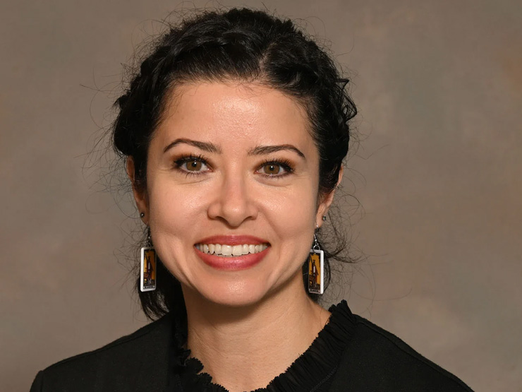 Assistant Professor of Philosophy and Africana Studies Tiffany Montoya standing against beige background for portrait.