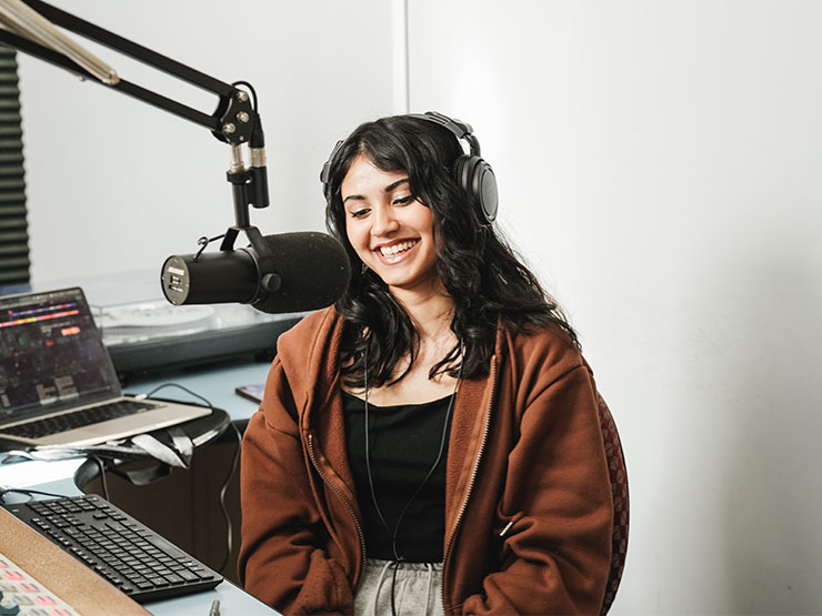 A Muhlenberg College students smiles while speaking into a mic at the WMUH radio station.