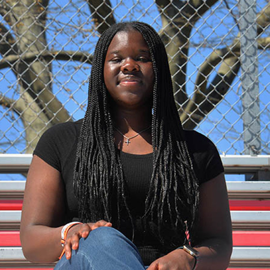 Erica Borbi smiles while seated on bleachers.
