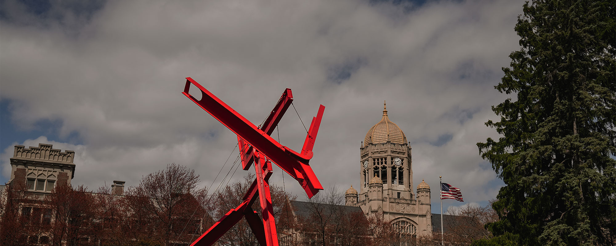 Red modern sculpture Victors Lament stands in front of the Haas clocktower on the campus of Muhlenberg College.