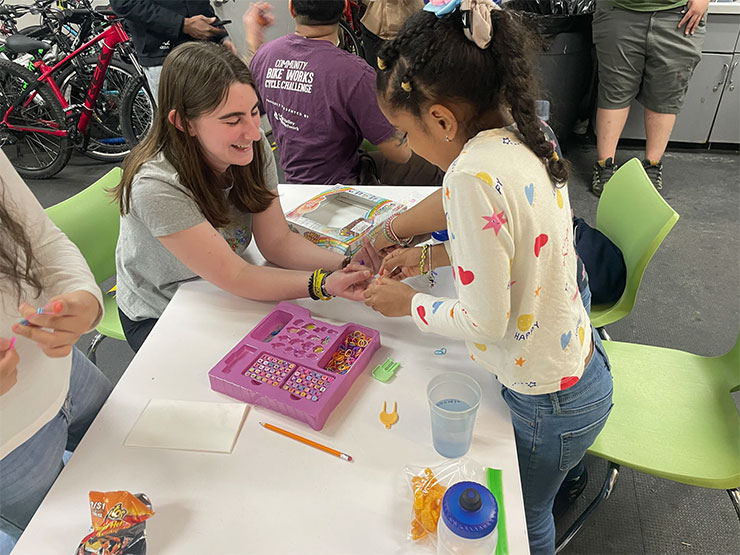 A college student works with a young girl at a youth bike organization