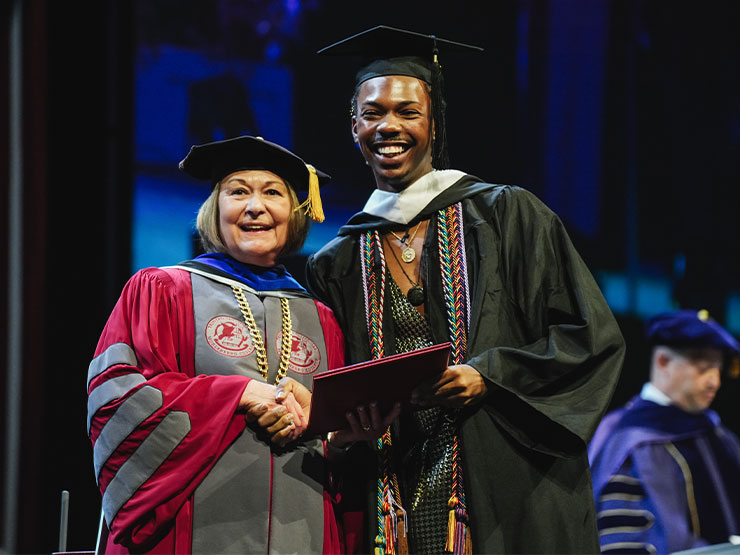 Muhlenberg College president Kathleen Harring poses with recent graduate at commencement ceremony.