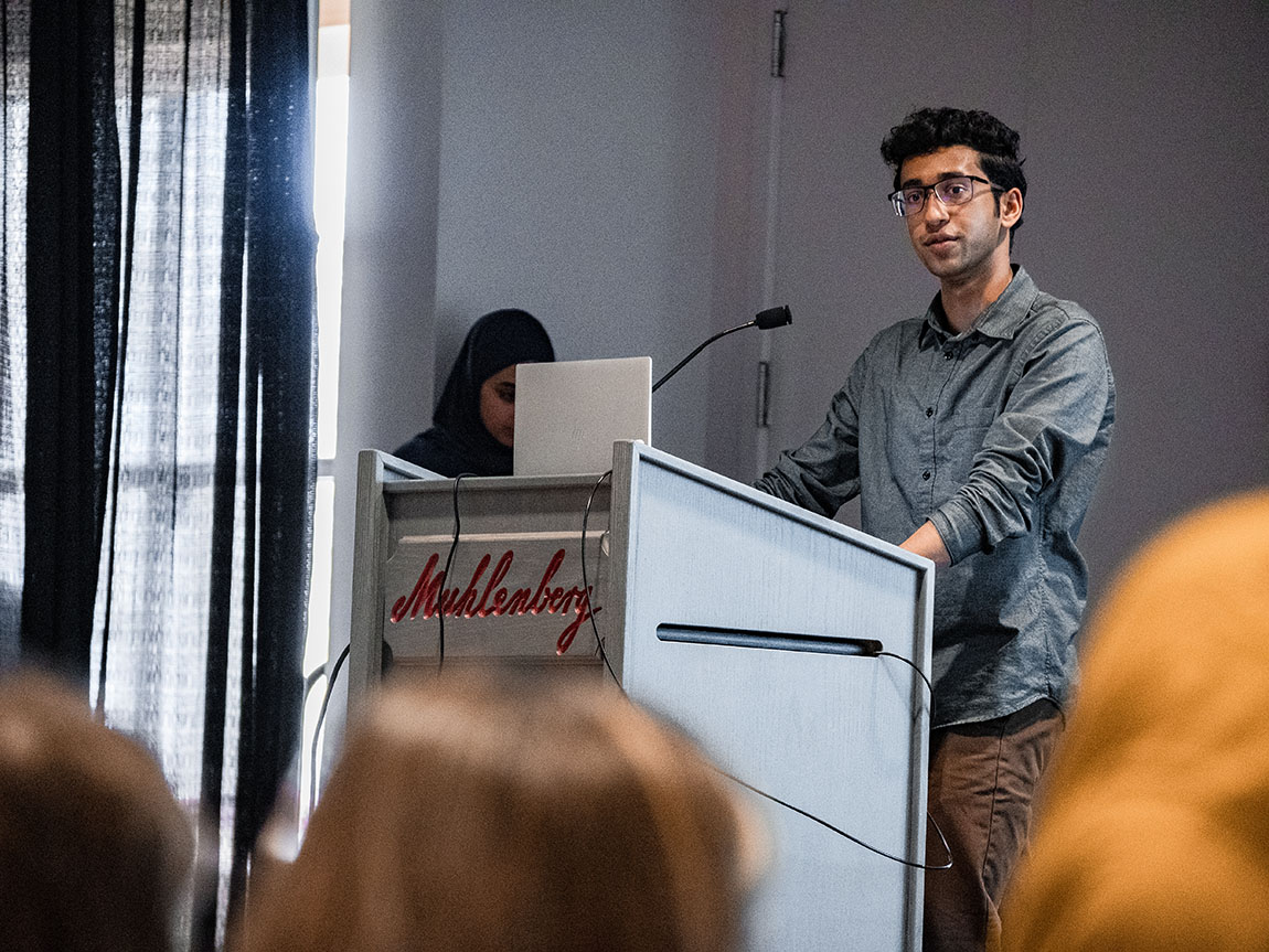 A college student stands at a podium that says Muhlenberg