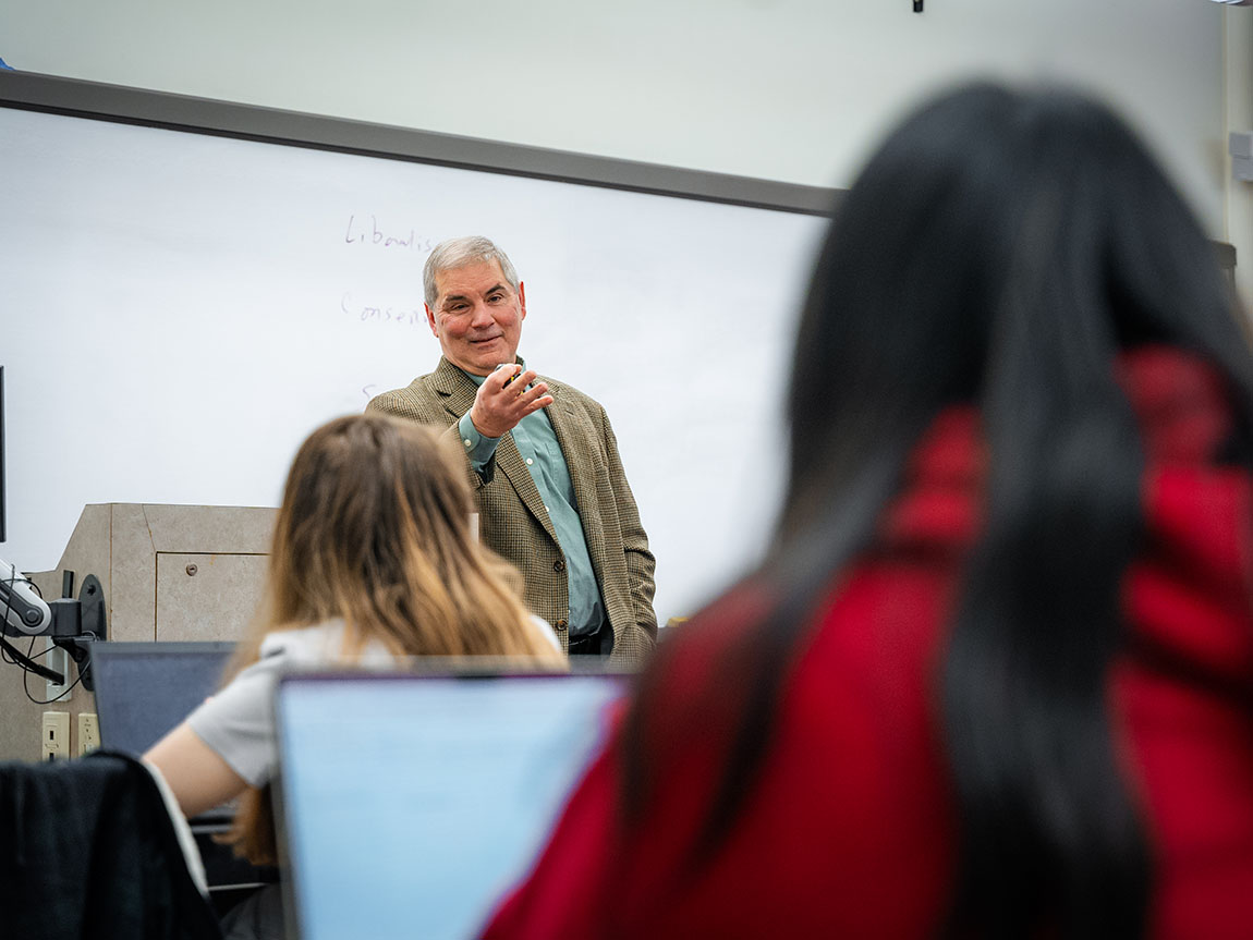 A college professor speaks in front of seated students during class