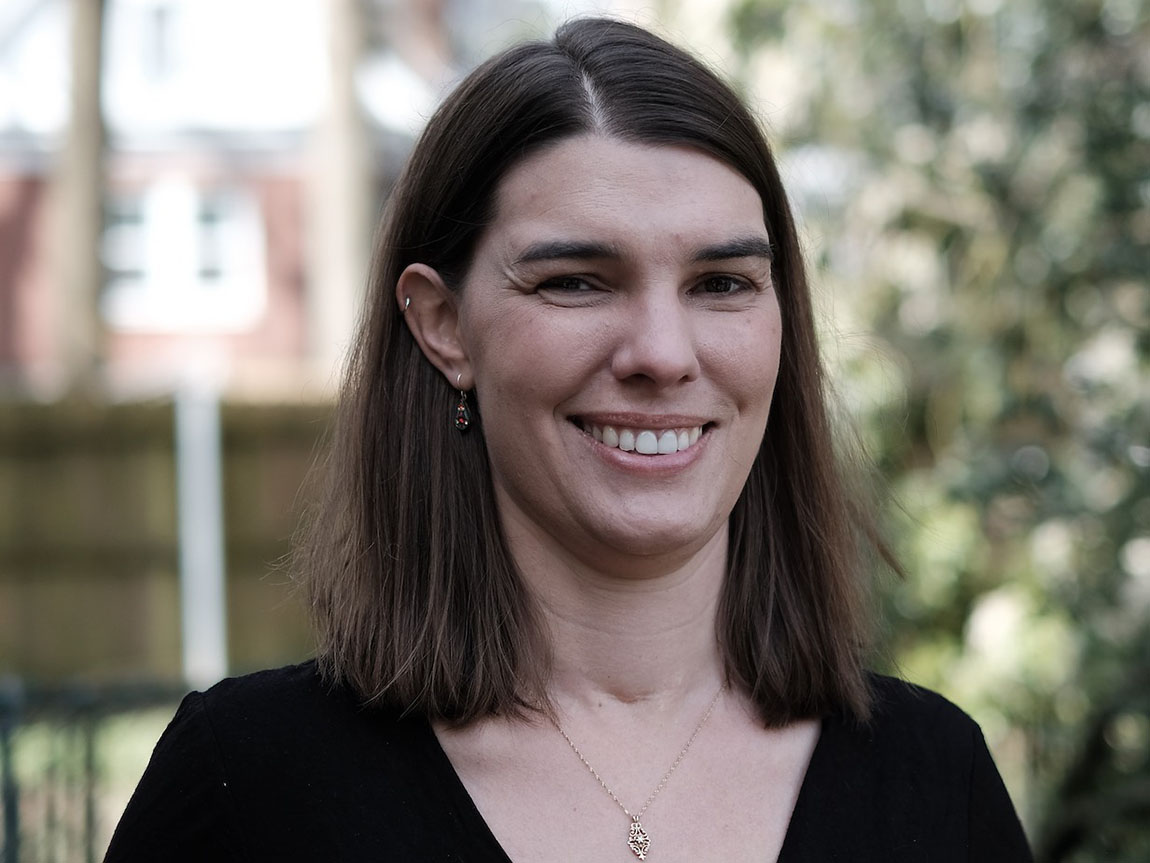 A headshot of a woman with dark brown hair in a black shirt