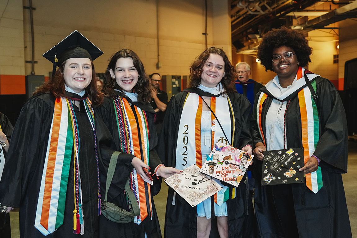 College students wait before their commencement ceremony and show their decorated caps.