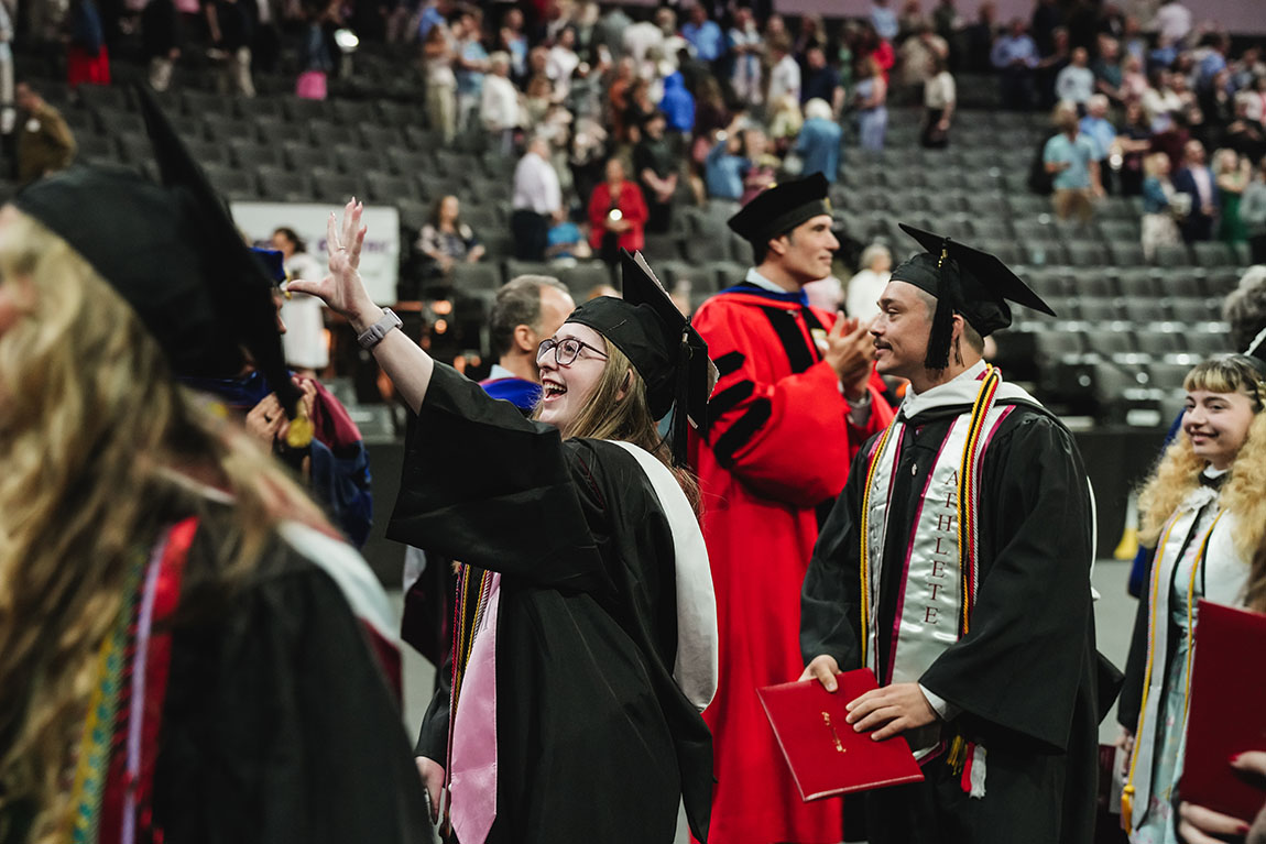 College graduates in caps and gowns file out of their commencement ceremony